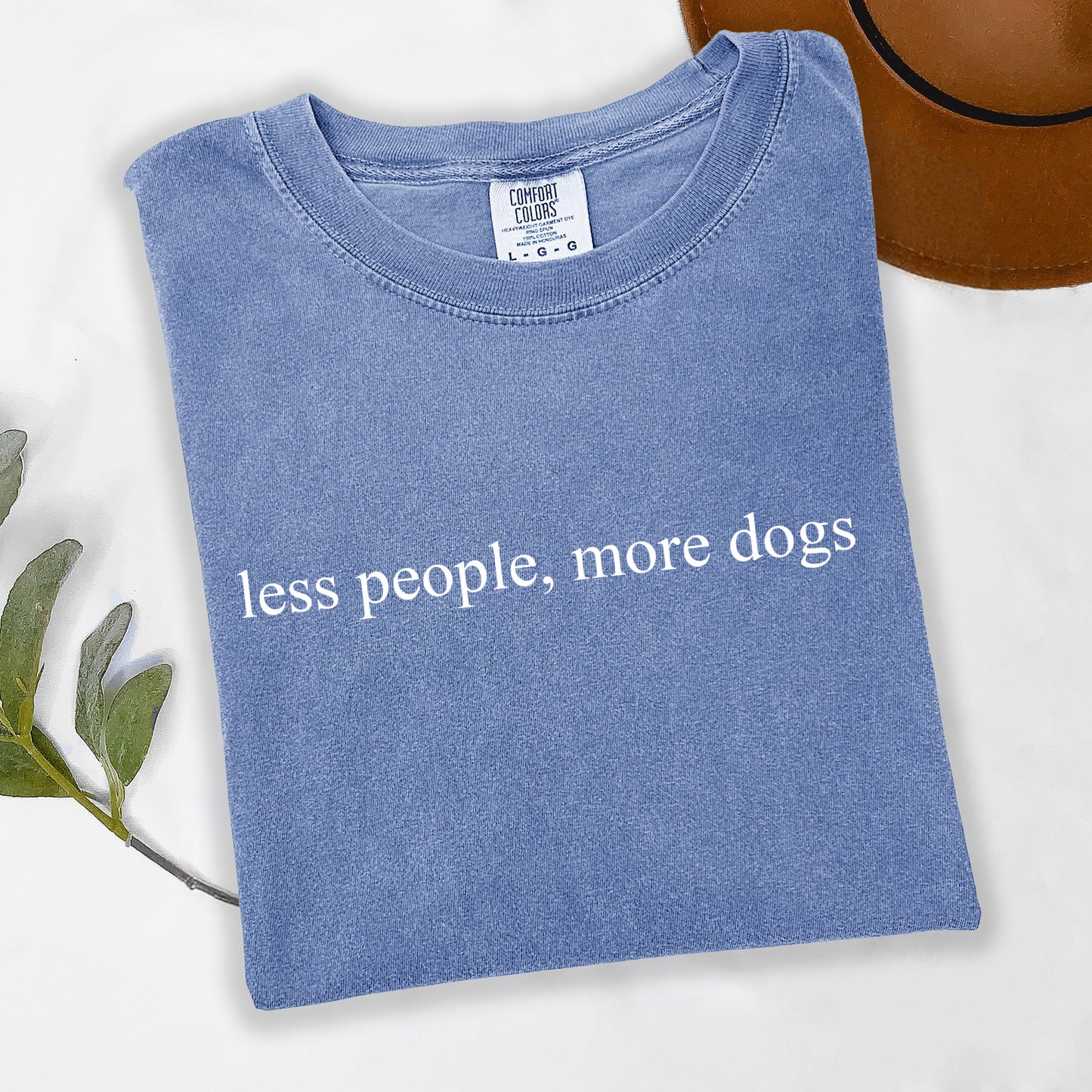 Blue t-shirt with 'less people, more dogs' text on a white background