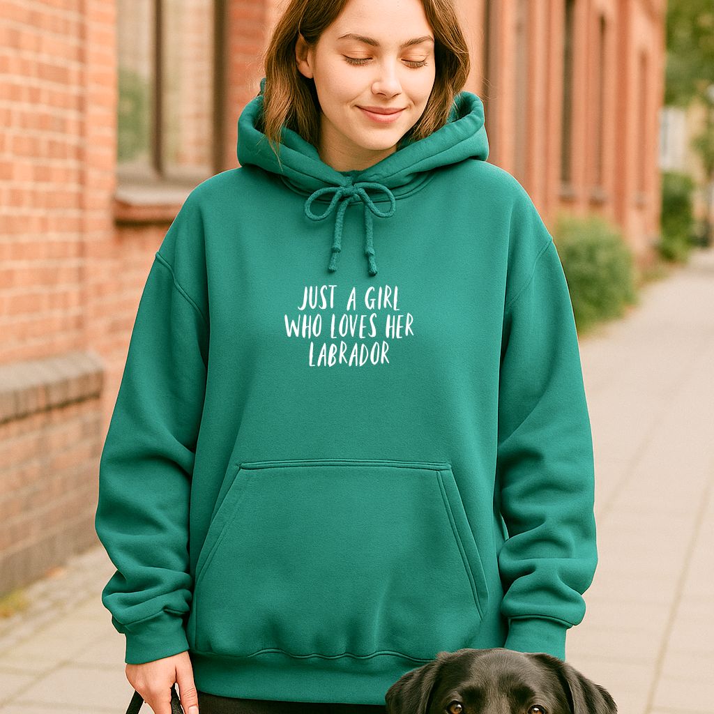Woman wearing a teal hoodie with text, standing next to a dog on a sidewalk.