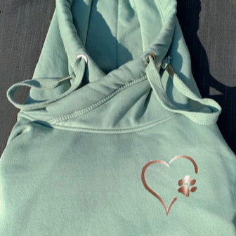 A green cowl neck hoodie with a rose gold heart and paw design on the front.