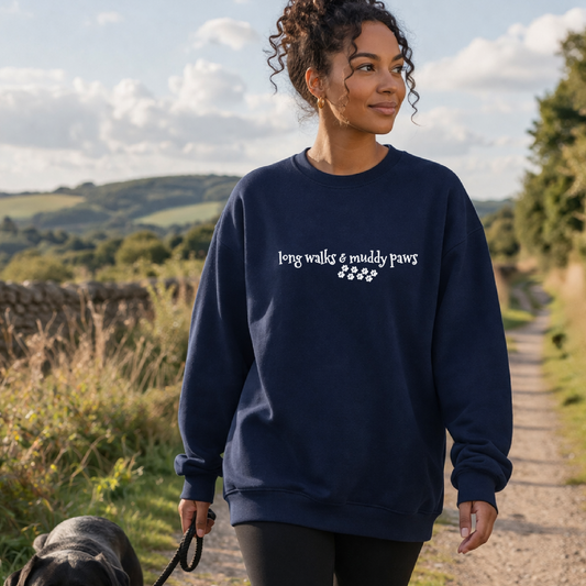 Woman walking a dog on a path with a navy sweatshirt featuring text and paw prints.