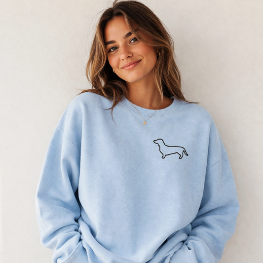 Woman wearing a light blue sweatshirt with a dog illustration on a plain background