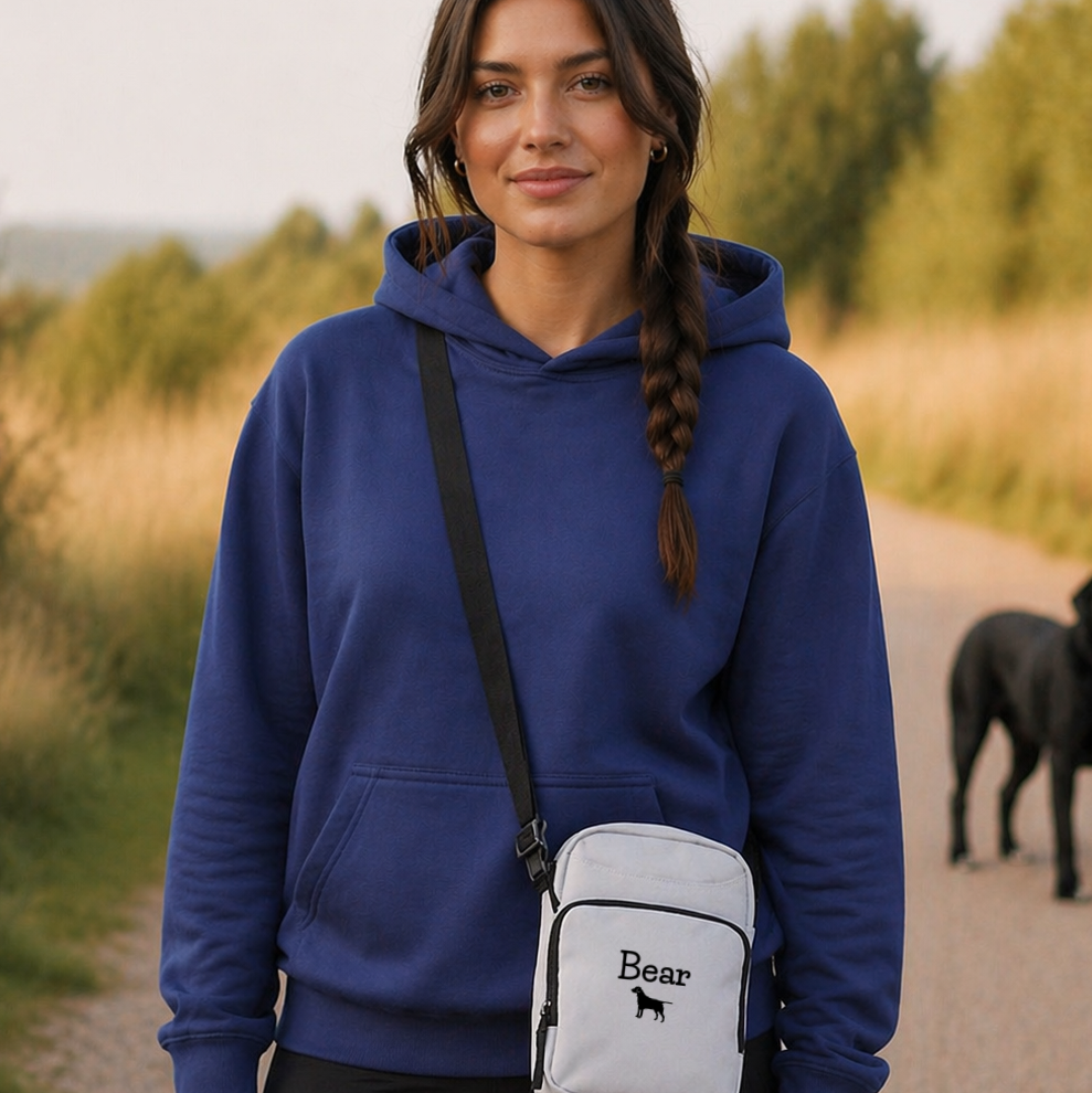 Woman wearing a blue hoodie with a white crossbody bag featuring 'Bear' branding, standing outdoors.