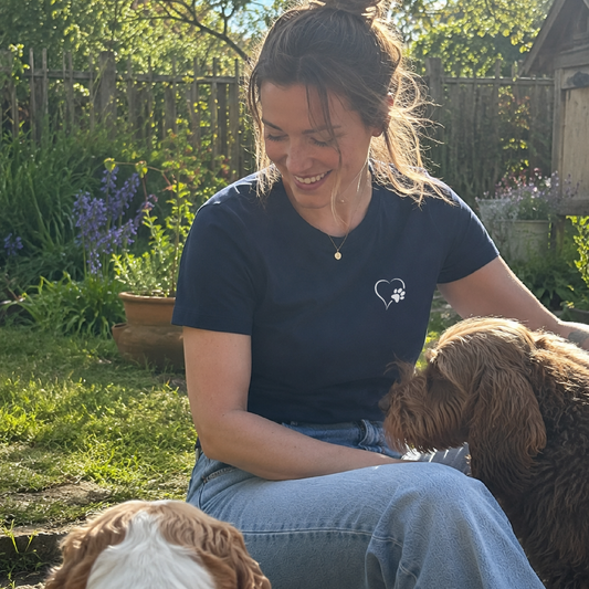 Woman sitting outdoors with two dogs in a garden setting