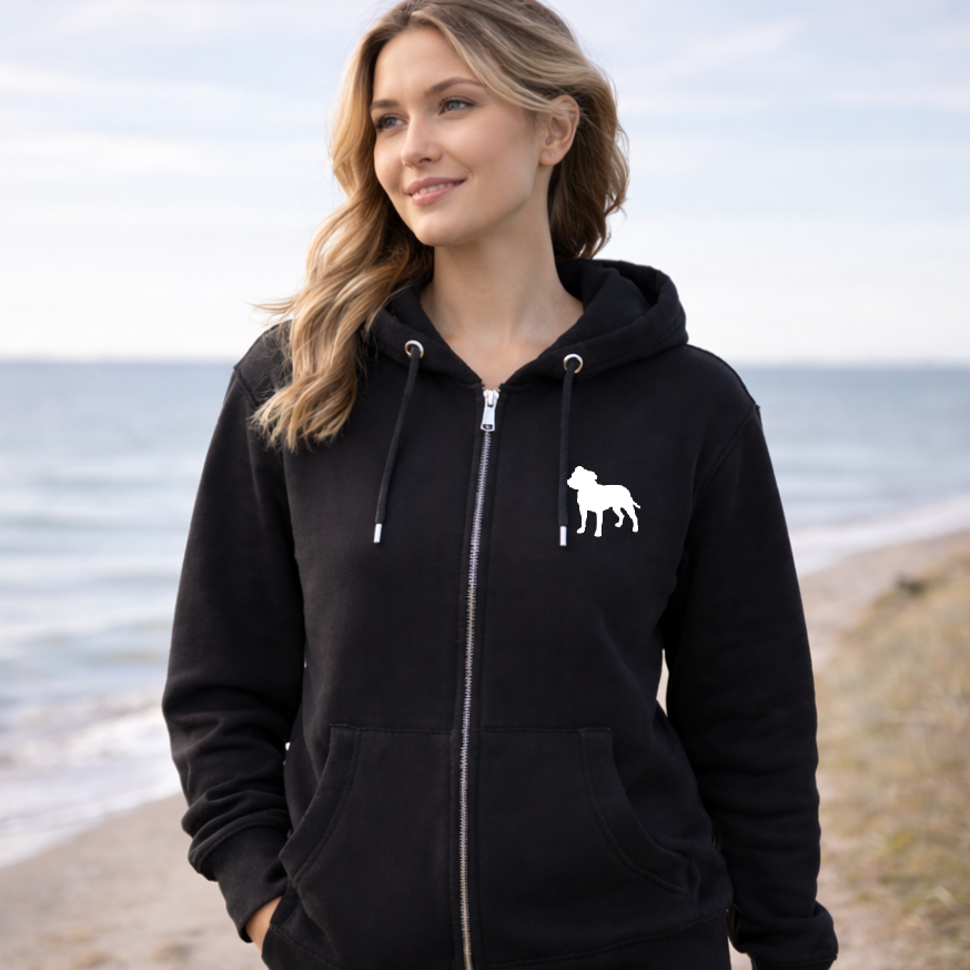 Woman wearing a black hoodie with a white dog logo on a beach