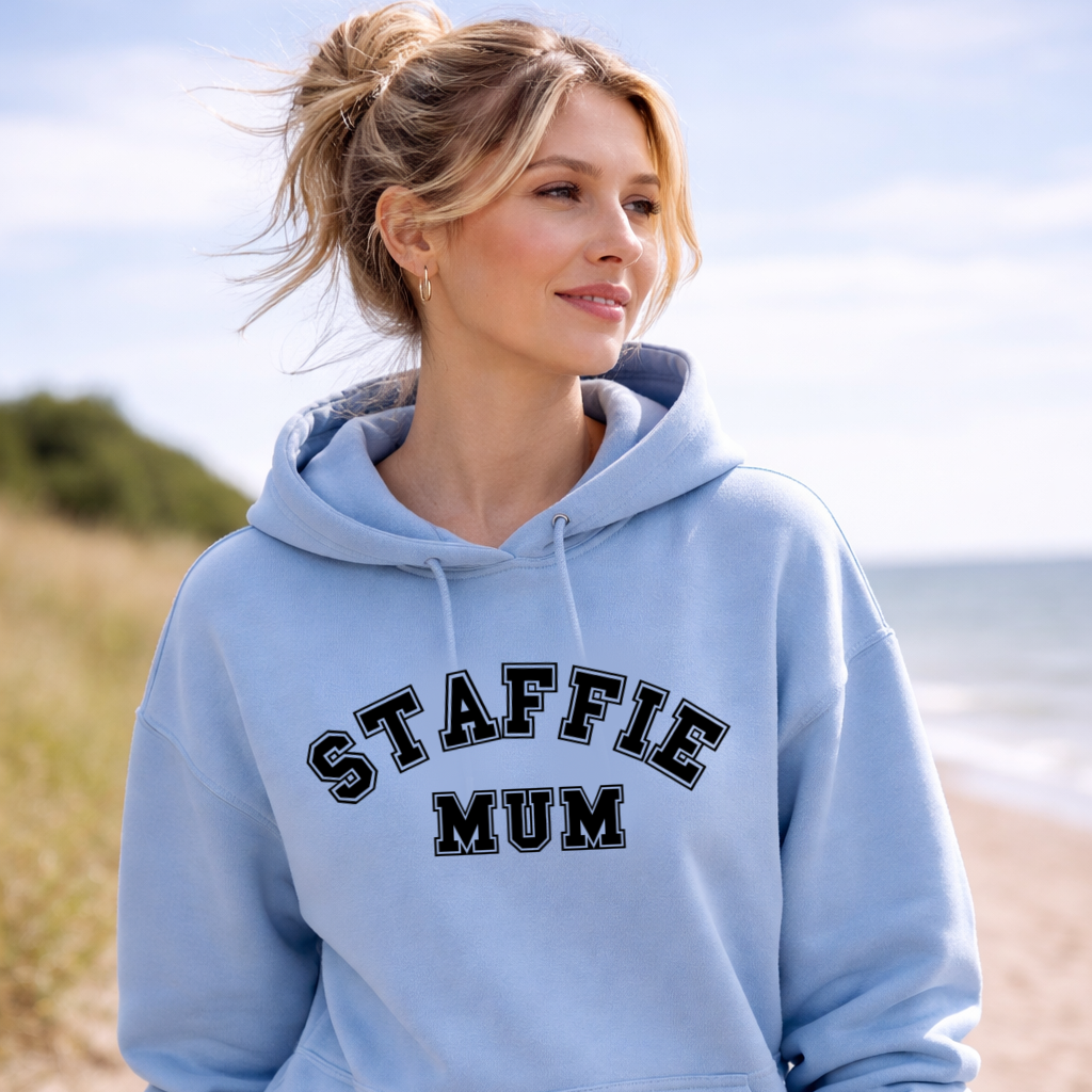 Woman wearing a light blue hoodie with 'STAFFIE MUM' text outdoors.