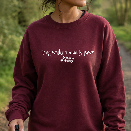 Person wearing a maroon sweatshirt with 'long walks & muddy paws' text, standing outdoors.