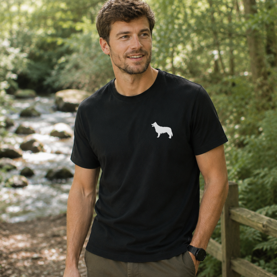 Man wearing a black t-shirt with a white dog logo in a forest setting