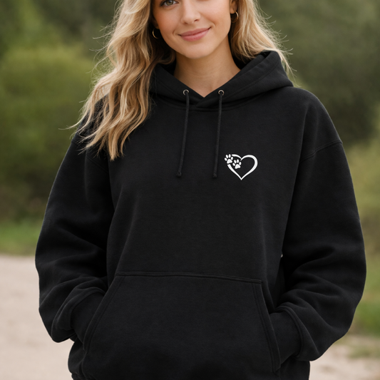 Person wearing a black hoodie with a heart and paw print design outdoors.