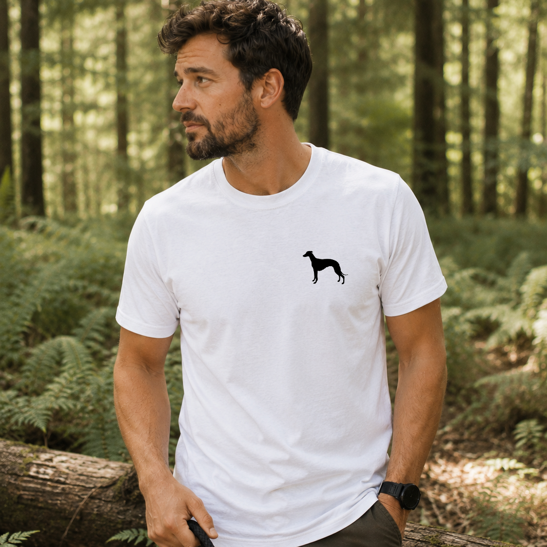 Man standing in a forest wearing a white t-shirt with a black silhouette design.